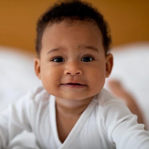 closeup-portrait-smiling-cute-little-black-baby-relaxing-bed